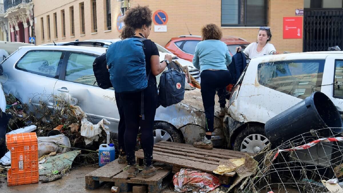 <p>Residentes pasan junto a coches apilados tras las inundaciones mortales en Sedavi, al sur de Valencia, este de España, el 30 de octubre de 2024 - PHOTO/AFP/José Jordán</p>