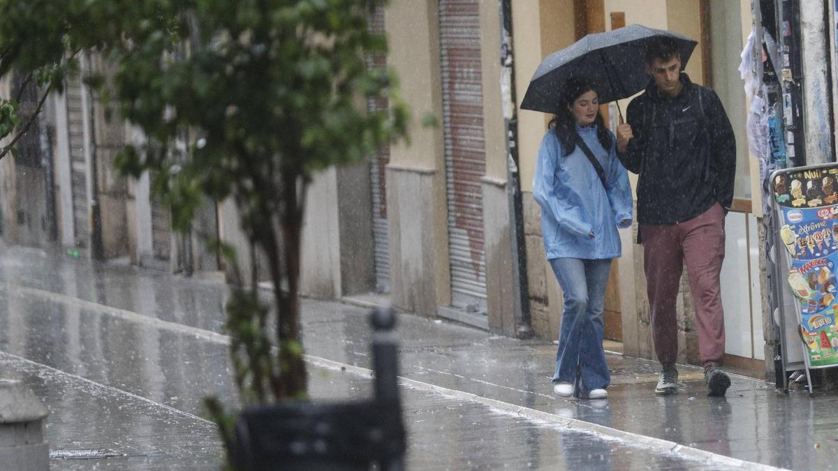 Dos jóvenes paseando bajo la lluvia este pasado sábado en la ciudad de València.