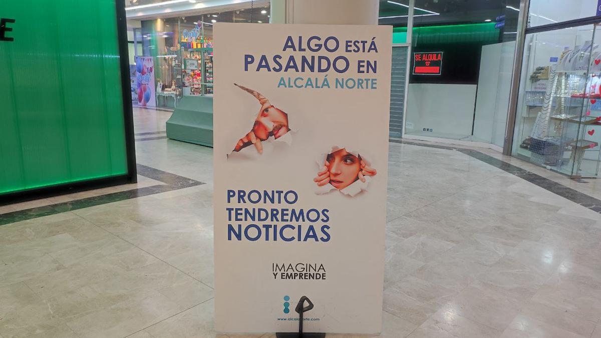 Cartel con los mensajes algo está pasando en Alcalá Norte y pronto tendremos noticias junto a un local en alquiler de este centro comercial de Ciudad Lineal, en Madrid.
