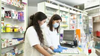 Mujeres jóvenes con mascarilla trabajando en farmacia