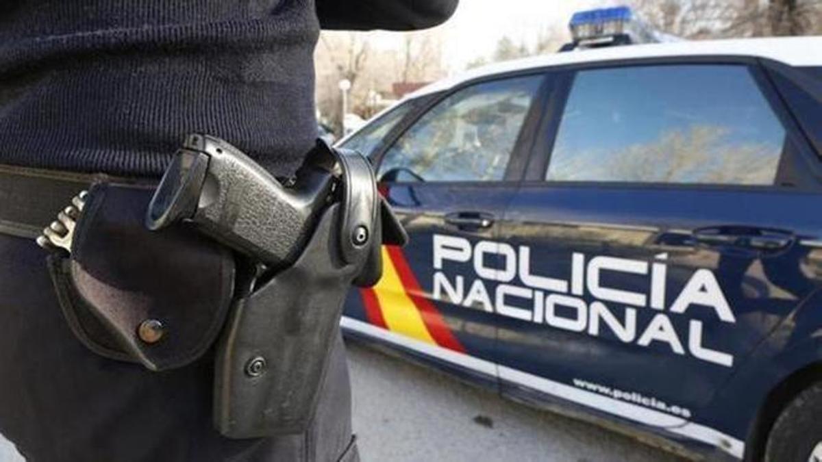 Un agente de la Policía Nacional, junto al coche patrulla.