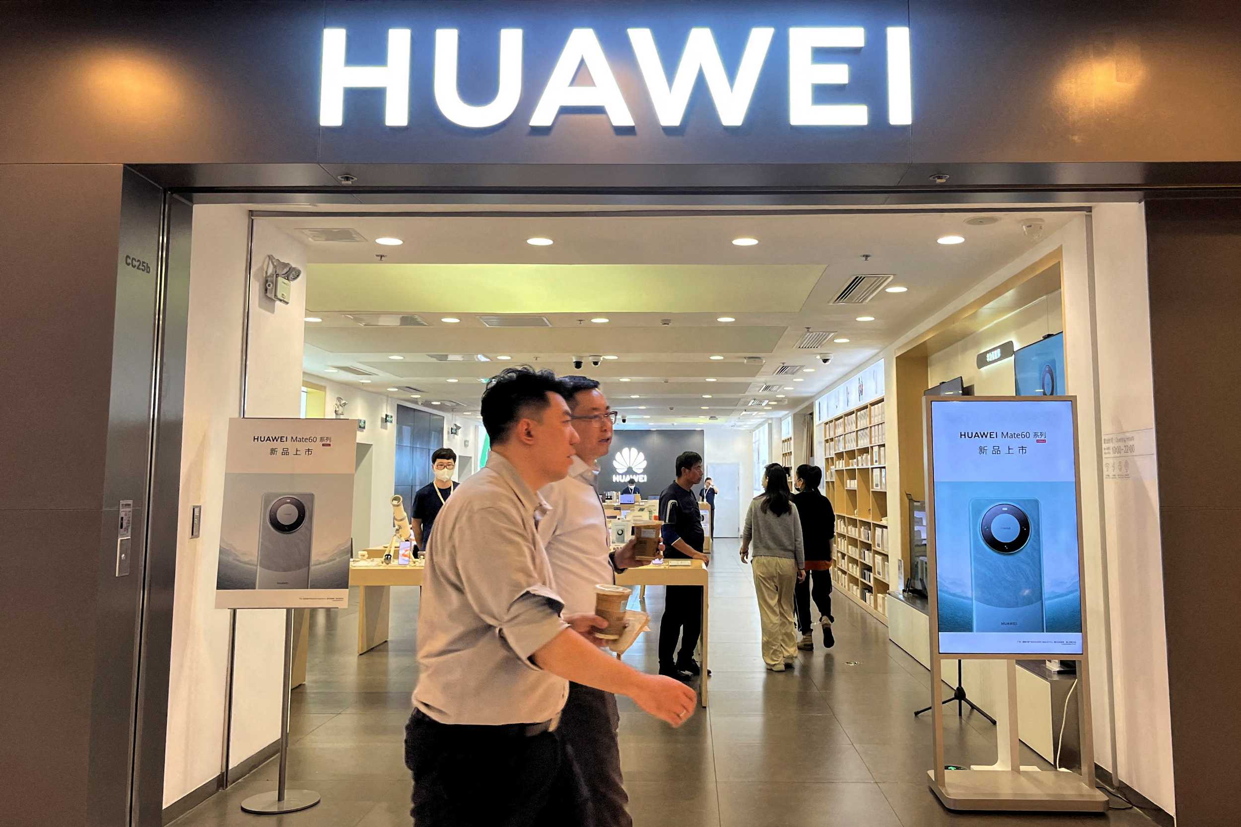 People walk past a Huawei store with advertisements for the Mate 60 series smartphones