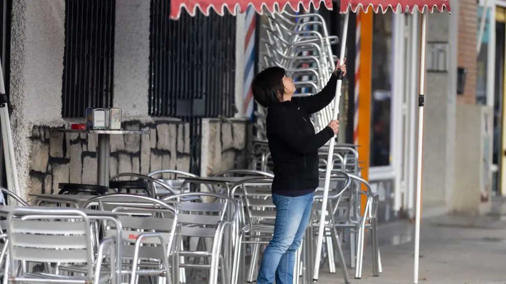 Una camarera levanta el toldo de un bar en Madrid.