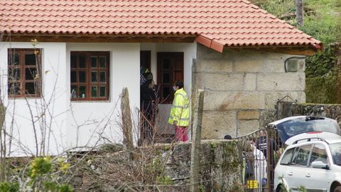 La acusada del crimen de Cortegada (con un chubasquero amarillo) entrando en su casa durante la reconstrucción del crimen